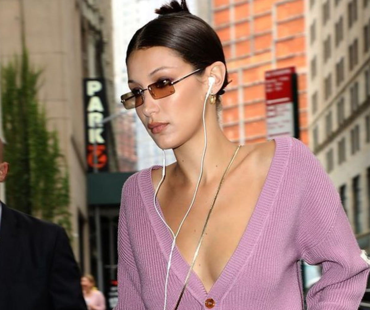Woman wearing a purple sweater with a deep neckline in an urban setting